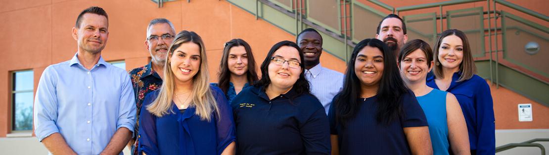 A group of diverse students and staff stand smiling at Northwest Campus