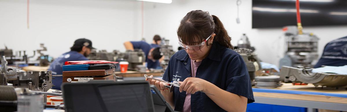 An aviation student works on a device inside an aviation classroom